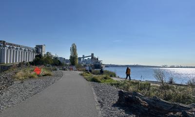 Paved mixed use trail along a waterfront with  grain elevators and shipping terminals alongside